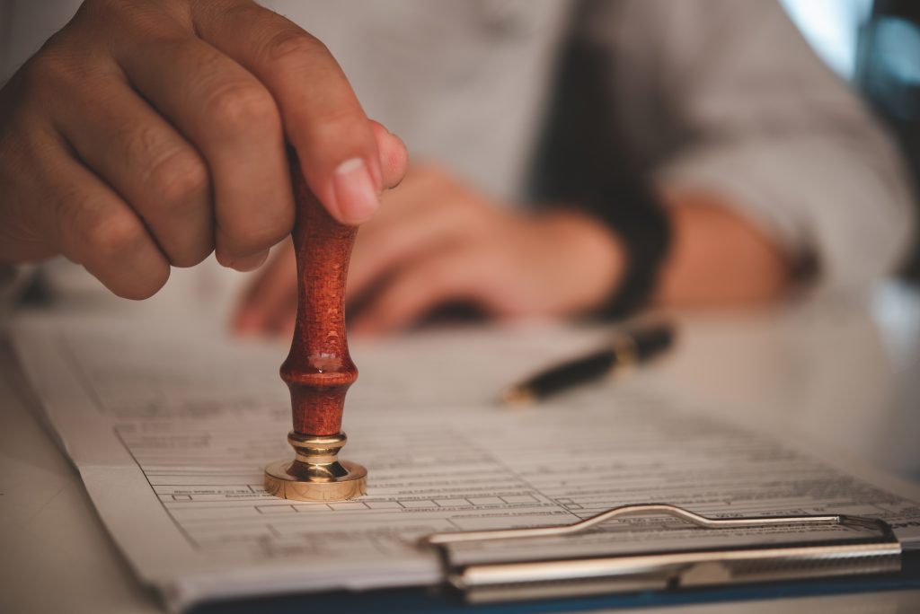 businessman hand stamping approved on certificate document contract in office.